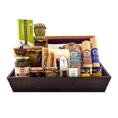 A wooden gift basket box containing various pork-free charcuterie items including duck salami, bison salami, dried apricots, organic dried cranberries, cashews, quince paste, mustards, cornichons, and olives.