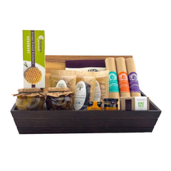 A wooden gift basket containing a variety of gourmet food items, including packaged salami, antipasti, crackers, and other snacks.